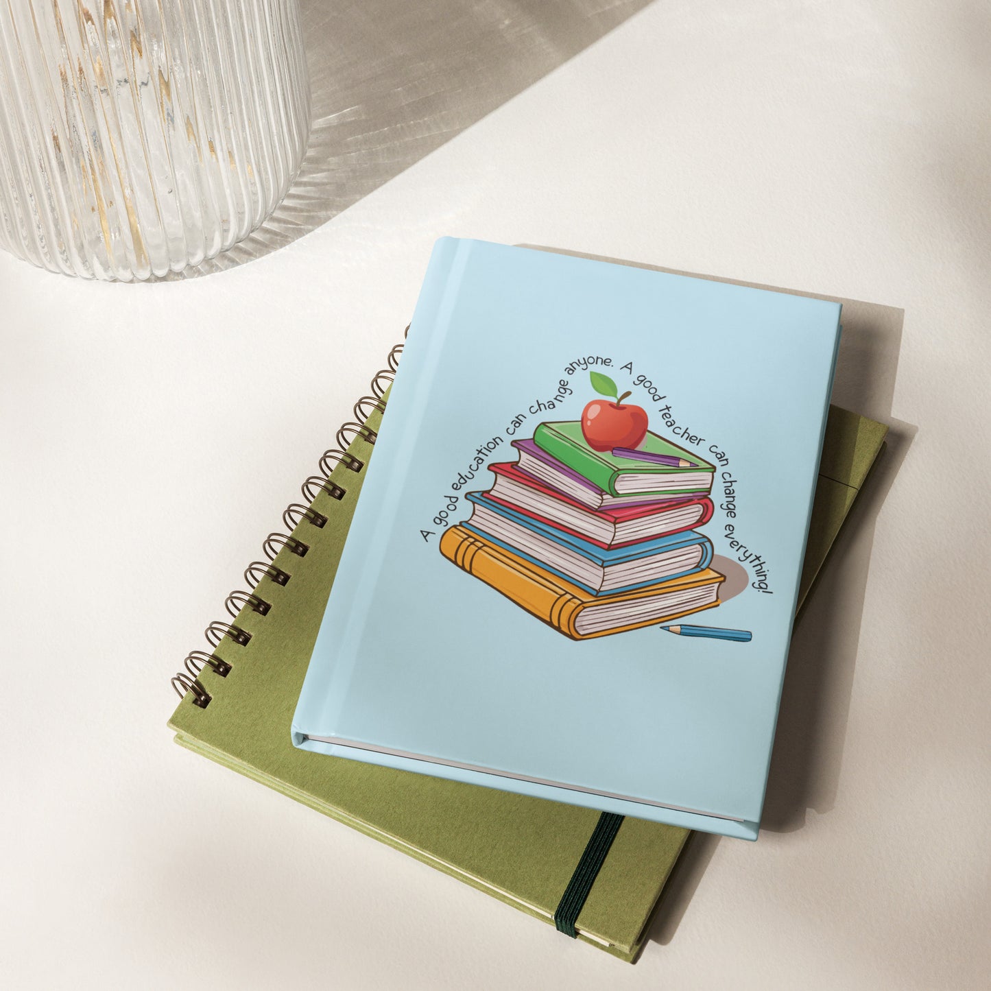 Light blue hardcover lined journal that says, 'A good education can change anyone, a good teacher can change everything' around a multicolored stack of books with an apple on top.