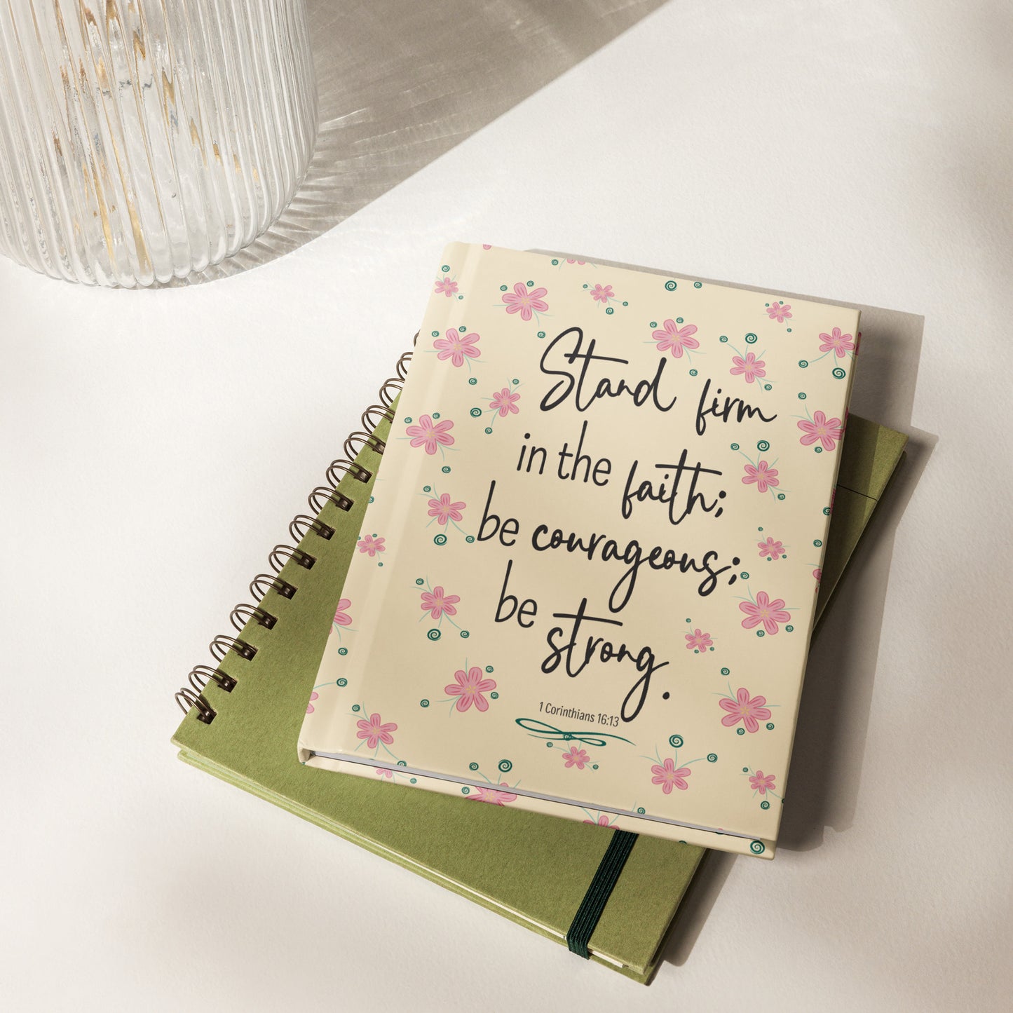 Cream hardcover lined journal with pink flowers scattered with Stand firm in the faith; be courageous; be strong, 1 Corinthians 16:13.