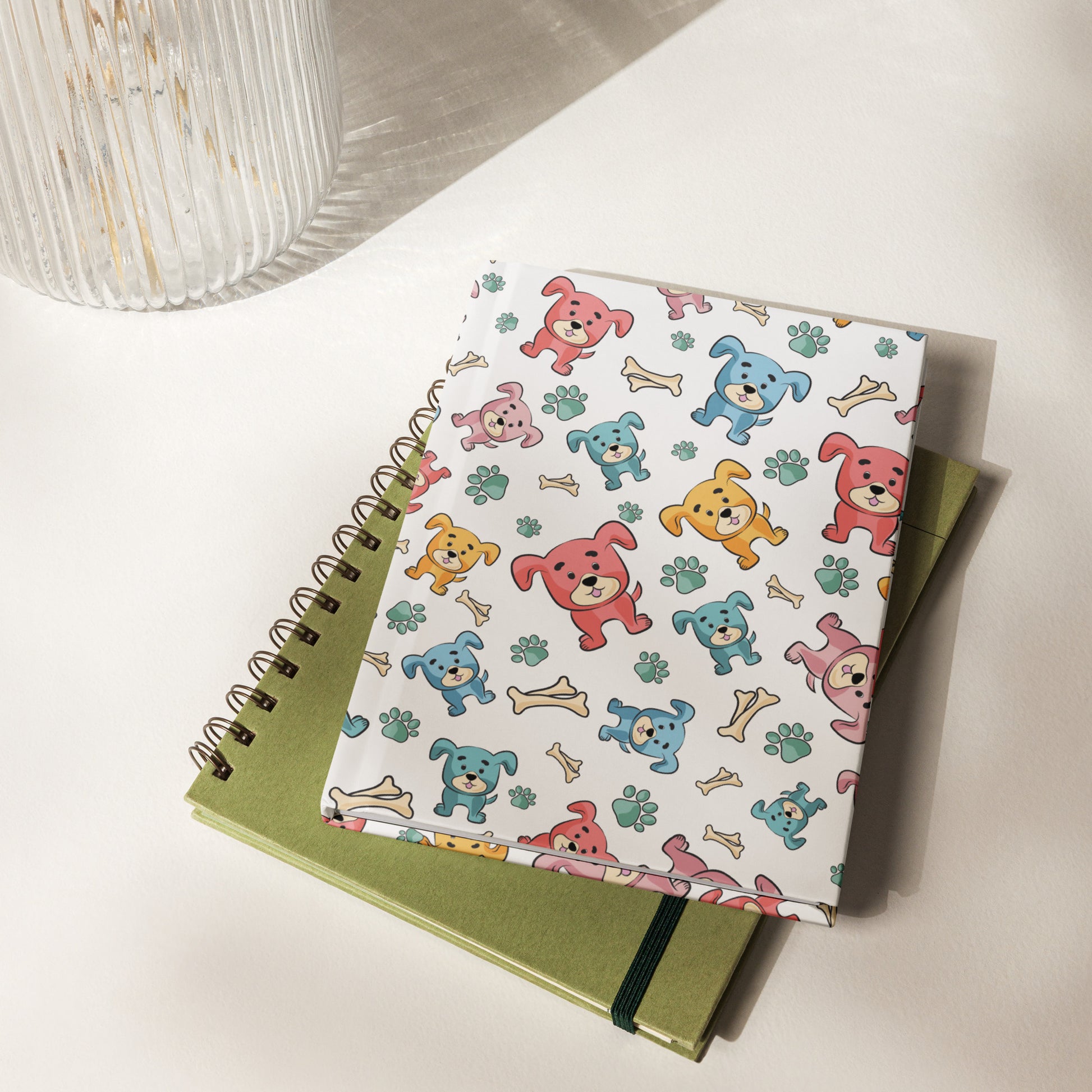 Hardcover Lined Journal with multi-colored puppies with bones and paws tossed around the full cover. 