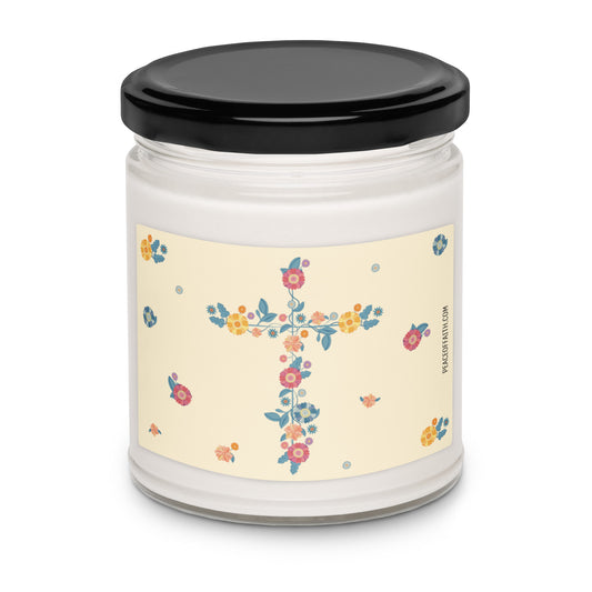 Clean cotton scented white soy candle with a label with a floral Christian cross and flowers scattered around. 