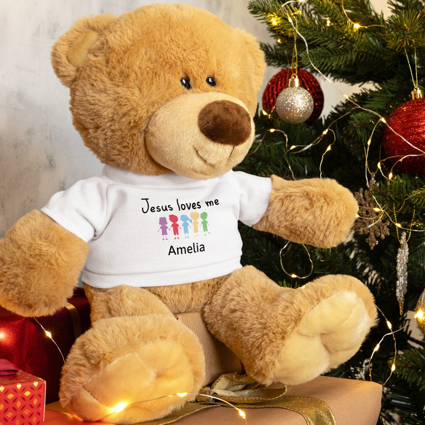 Personalized brown Teddy Bear wearing a white T-shirt that says  Jesus Loves Me with child's name and colorful cartoon little kids holding hands. 