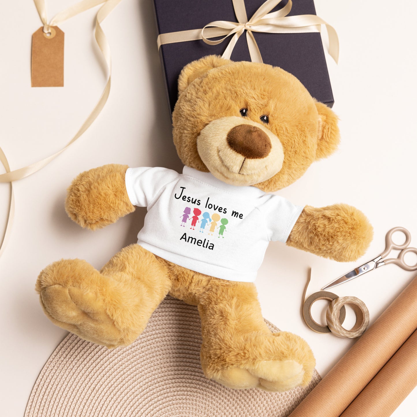 Personalized brown Teddy Bear wearing a white T-shirt that says  Jesus Loves Me with child's name and colorful cartoon little kids holding hands. 