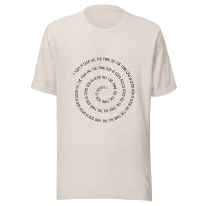 Heather dust short sleeve t-shirt that has a spiral of the words 'God is good all the time all the time God is good', with two small hearts one at the start of the spiral and one at the end in the middle.