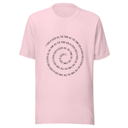 Soft pink short sleeve t-shirt that has a spiral of the words 'God is good all the time all the time God is good', with two small hearts one at the start of the spiral and one at the end in the middle.