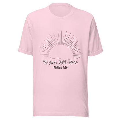 Soft pink unisex short sleeve t-shirt that has a sun with many rays and underneath says 'Let your light shine', Matthew 5:16.